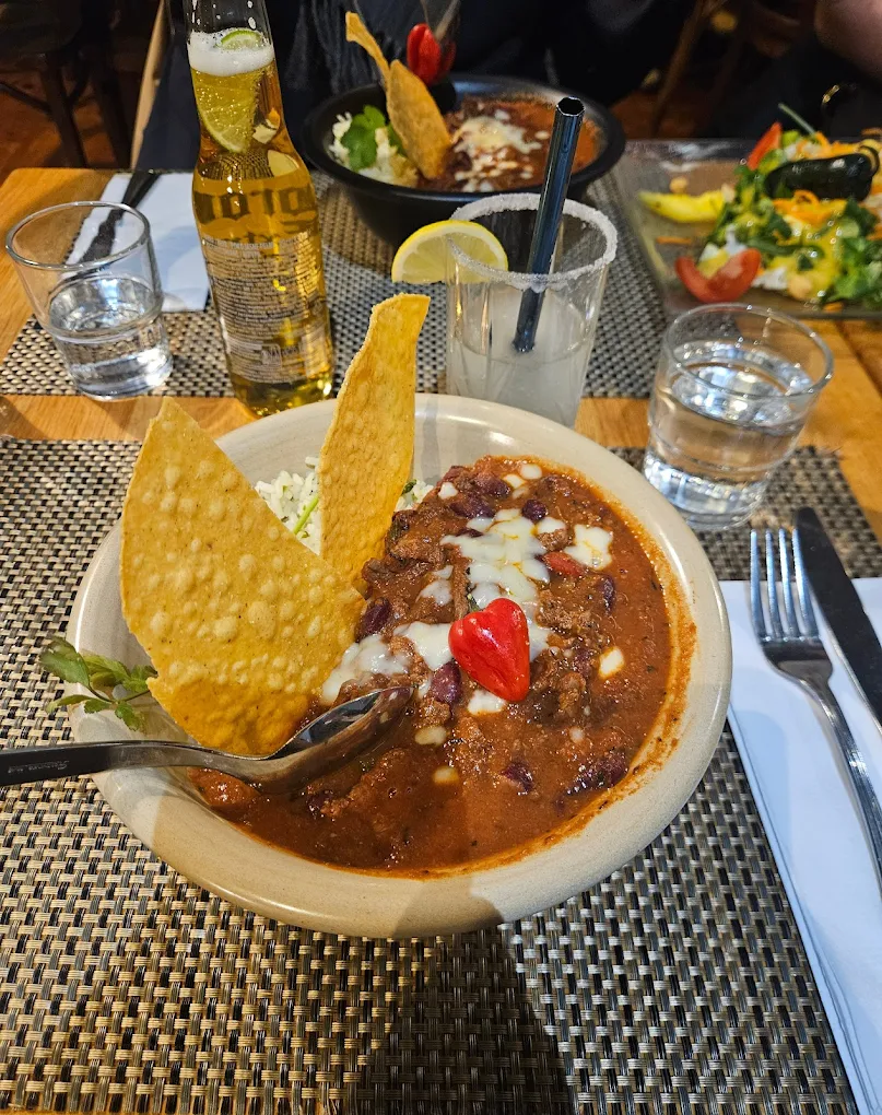 Chili con carne maison servi en bol avec chips de maïs et une bière, au restaurant Le Mexicain.