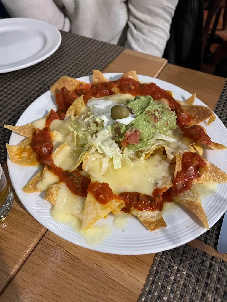 Nachos gratinés au fromage fondu, salsa, guacamole et crème, servis au Mexicain à Genève.