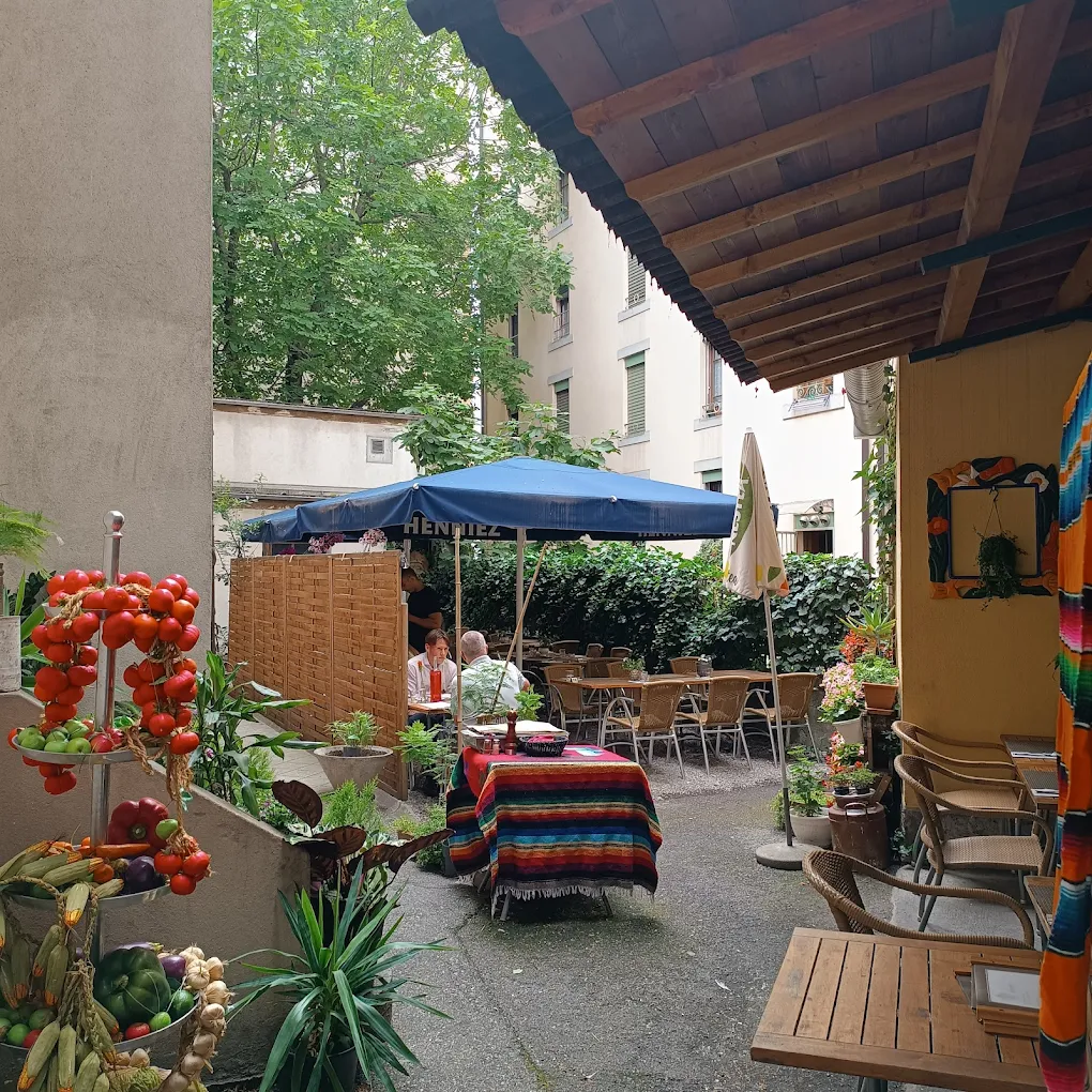 Patio-terrasse ombragé du Mexicain : tables habillées de plaids mexicains, parasol et plantes.
